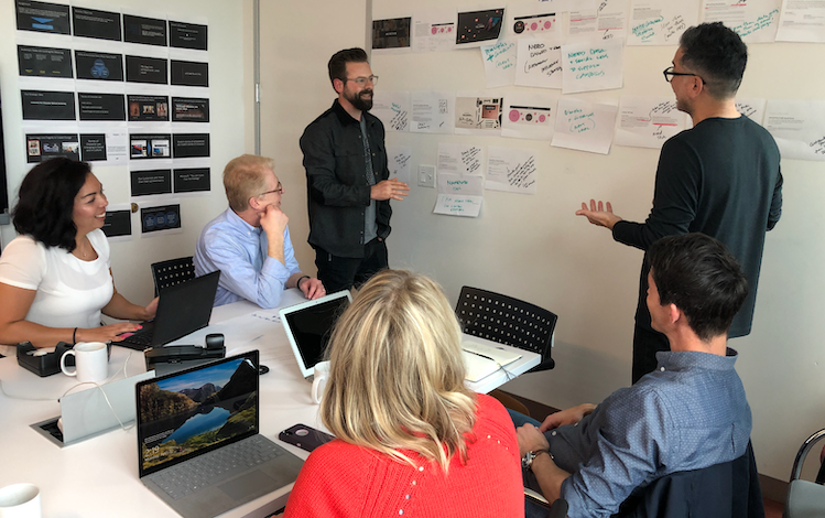 Ray Page and team around a whiteboard - WE Communications 