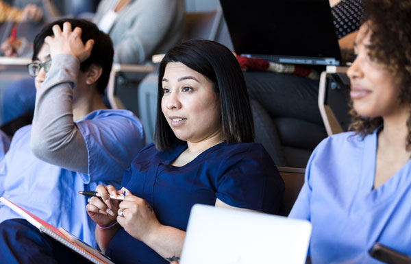 woman writing down notes in conference