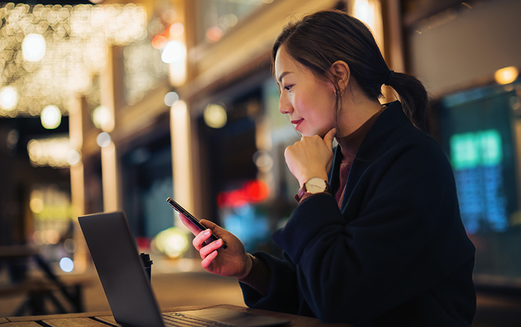 woman using phone infront of laptop