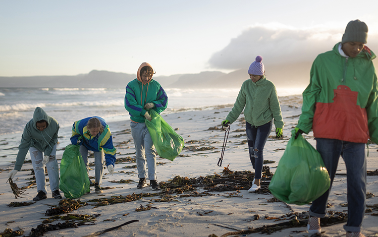 people picking up trash on the beach